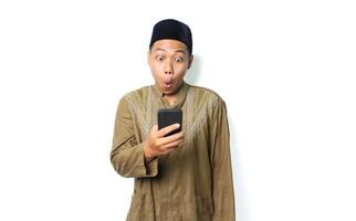 shocked asian muslim man wearing islamic dress holding mobile phone isolated on white background photo