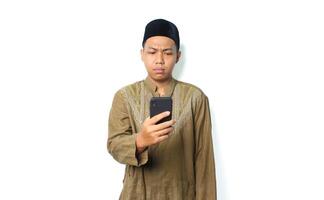 confused asian muslim man read message using smartphone show thinking expression isolated on white background photo