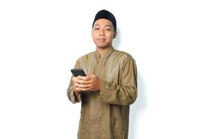 side view of pleased asian muslim man read a message using mobile phone isolated on white background photo
