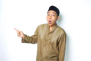 shocked asian muslim man pointing to beside isolated on white background photo