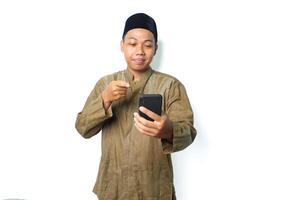 calm asian muslim man pointing to mobile phone hold on hands isolated on white background photo