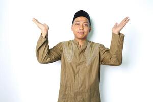 pleased asian muslim man wearing koko clothes presenting with open palm to above isolated on white background photo