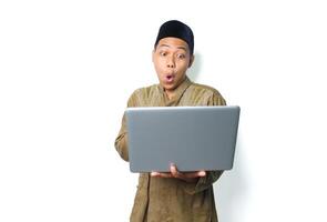 surprised asian muslim man wearing islamic dress holding laptop isolated on white background photo