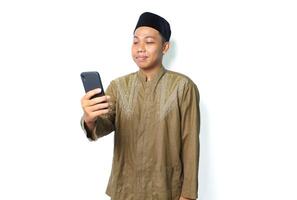 side view of pleased asian muslim man read a message using mobile phone isolated on white background photo