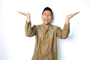 ecstatic asian moslem man wearing islamic dress raising palm to above presenting with laughing expression isolated on whiote background photo