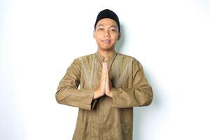 peaceful asian muslim man give greeting wearing koko clothes in eid al fitr celebration isolated on white background photo