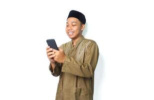 happy asian muslim man surfing in cyberspace using mobile phone isolated on white background photo