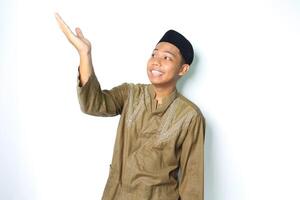 happy asian muslim man wearing koko clothes presenting to above with open palms isolated on white background photo