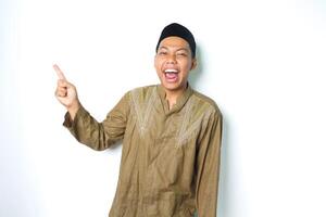 excited asian moslem man screaming with pointing to above wearing islamic dress isolated on white background photo