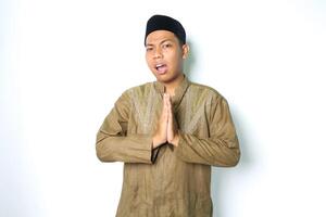 confused asian muslim man give greeting in eid al fitr celebration wearing koko clothes isolated on white background photo