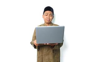 sad asian muslim man holding laptop with crying expression isolated on white background photo