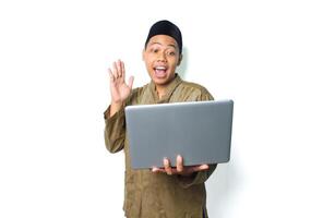 attractive asian muslim man surprised with raising hand looking at laptop isolated on white background photo