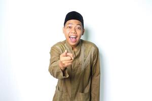 surprised asian muslim man wearing islamic clothes pointing at camera isolated in white background photo