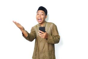 funny asian muslim man screaming while presenting empty space with holding moblie phone isolated on white background photo