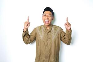 excited asian moslem man screaming with pointing to above wearing islamic dress isolated on white background photo