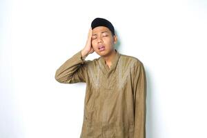 stressed asian muslim man wearing koko clothes hold his head feeling dizzy isolated on white background photo