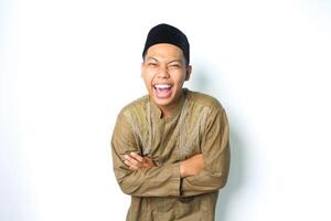 ecstatic asian muslim man laughing with folded arms wearing islamic dress isolated on white background photo