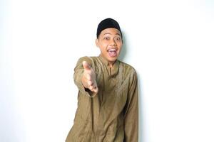 asian muslim man looks surprised while offer handshake at camera isolated on white background photo