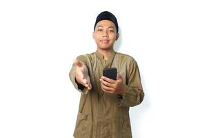 pleased asian muslim man offering handshake with holding smartphone isolated on white background photo
