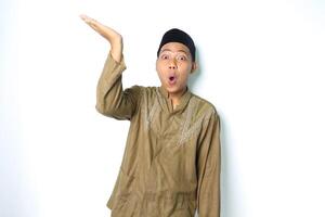 surprised asian muslim man presenting to above with open palm isolated on white background photo