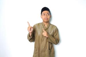 confused asian muslim man pointing to above looking away wearing koko clothes isolated on white background photo