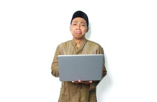sad asian muslim man holding laptop with crying expression isolated on white background photo