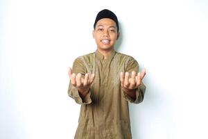 smiling asian muslim man wearing islamic dress presenting with open palm at camera isolated on white background photo