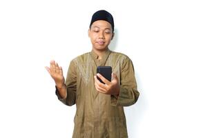 calm asian moslem man raising hand to praying when read message using mobile phone isolated on white background photo