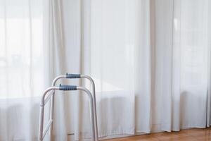 Cropped view of elderly man walking with frame at home, closeup. young male asian using medical equipment to move around his house. Disabled older person in need of professional help photo