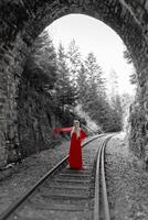 woman in a red dress in front of a railway tunnel photo