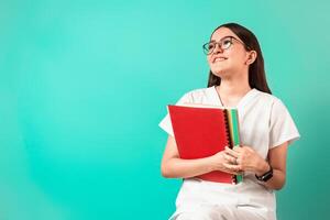 joven latinx mujer con lentes vistiendo salud uniforme participación libros. foto