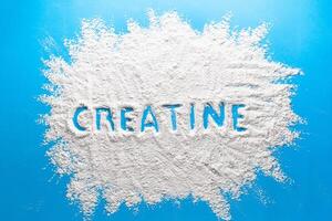 Scattered powder with the word creatine written on it on a blue background. photo