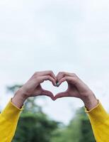 arm with sweater yellow making a heart with of hands,love concept. photo