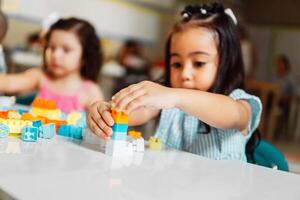 Little female children playing with colored blocks. photo