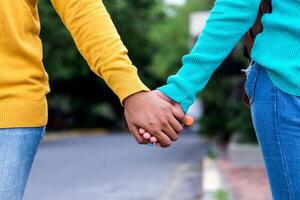 couple woman wearing sweater blue and yellow holding hands together photo