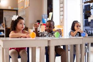 Three preschool children in a class of kindergarten. photo