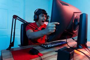 Anxious and angry professional gamer man screaming in front of a computer monitor. Concept mental health. photo