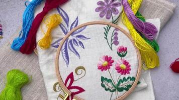 The process of hand embroidering a napkin with colored threads on white fabric. video