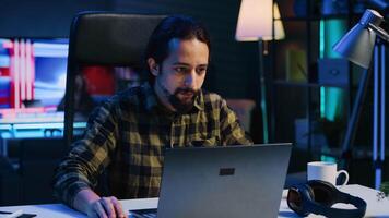 Freelancer sitting at home office desk and typing on laptop keyboard, doing his job. Remote worker using electronic device to send emails to customers from living room, camera A video