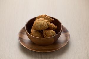 Thai-style curry puff in a dark brown wooden bowl. photo