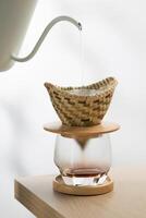 Pour hot water into the ground coffee in a dripper made of bamboo weave. photo