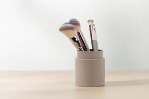 Various sizes of Rouge Brushes in pastel pink cup on a wooden table. photo