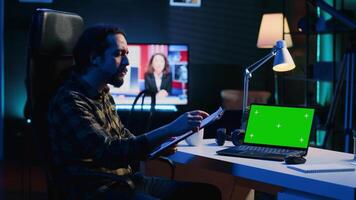 Man in home office checking statistical data financial graphs on documents files, crosschecking with mockup laptop. Remote employee comparing business graphics paperwork with green screen device video