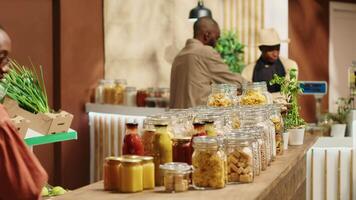 African american client examines bio homemade bulk products, looking to buy natural ethically sourced food alternatives for healthy nutrition. Woman shopping for goods at zero waste store. Camera A. video