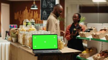 ordenador portátil corriendo aislado pantalla verde en monitor en tienda de comestibles almacenar, presentación blanco chromakey modelo en inalámbrico ordenador personal. clientela y vendedor comprobación orgánico éticamente de origen productos cámara una. video