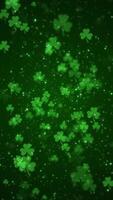 Vertical video - lucky shamrocks, shiny stars and glowing glittering particles on a dark green background. This Saint Patrick's Day celebration party background animation is full HD and looping.