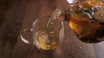 fruta chá é derramado para dentro uma vidro copo. café da manhã conceito. fresco quente ervas chá com hortelã e laranjas, desintoxicação bebida. video