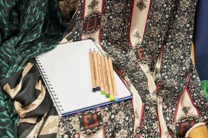 a notebook, pencils and a scarf on a table photo