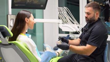 dentista muestra dentadura postiza con un soporte en su manos a el paciente video