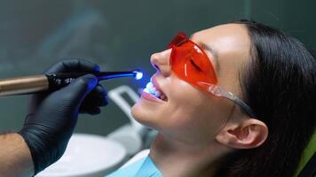 Young woman during dental filling drying procedure with curing UV light at dental clinic video